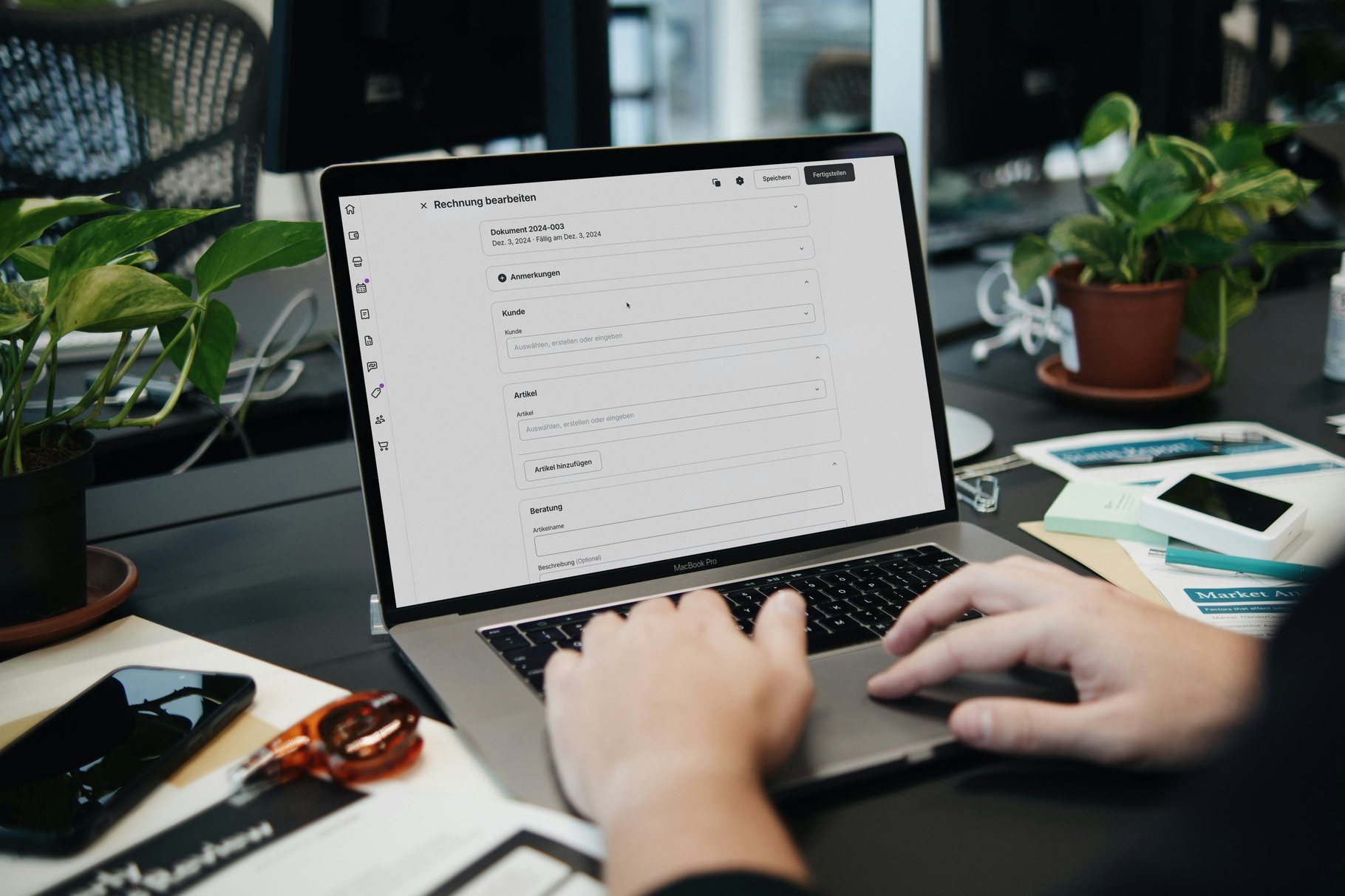 Hands working through a document on a laptop at a desk spread with papers